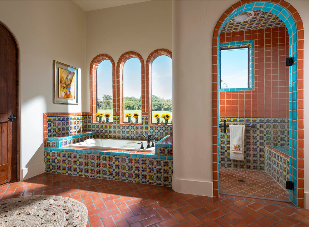 Cette photo montre une salle de bain principale sud-ouest américain avec un carrelage multicolore, des carreaux en terre cuite, tomettes au sol, une baignoire posée, une douche d'angle, un mur beige, une cabine de douche à porte battante et une fenêtre.