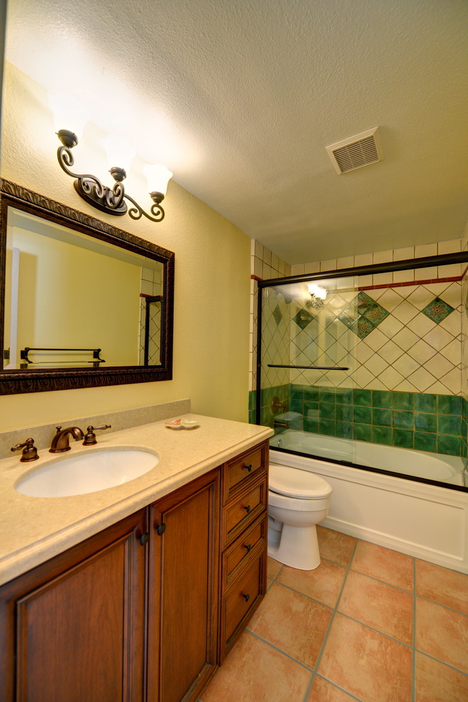Aménagement d'une salle de bain méditerranéenne en bois brun avec un placard à porte affleurante, une baignoire en alcôve, un combiné douche/baignoire, WC séparés, un carrelage jaune, des carreaux de céramique, un mur jaune, tomettes au sol, un lavabo encastré, un plan de toilette en quartz modifié, un sol rose, une cabine de douche à porte coulissante et un plan de toilette beige.