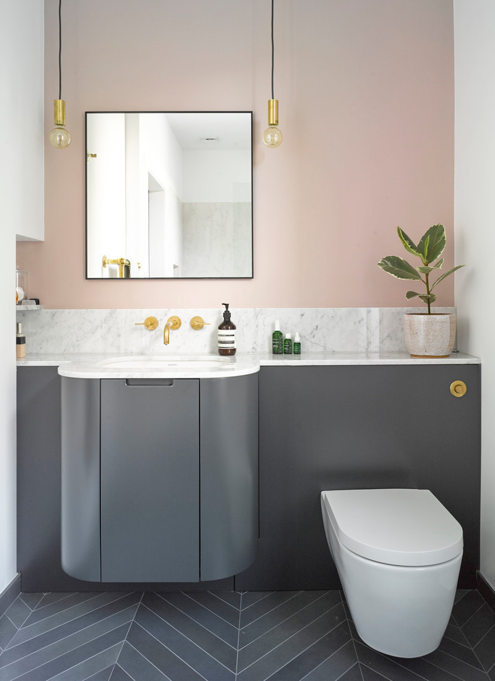 Imagen de cuarto de baño actual con armarios con paneles lisos, puertas de armario grises, paredes rosas, lavabo bajoencimera, suelo gris y encimeras blancas
