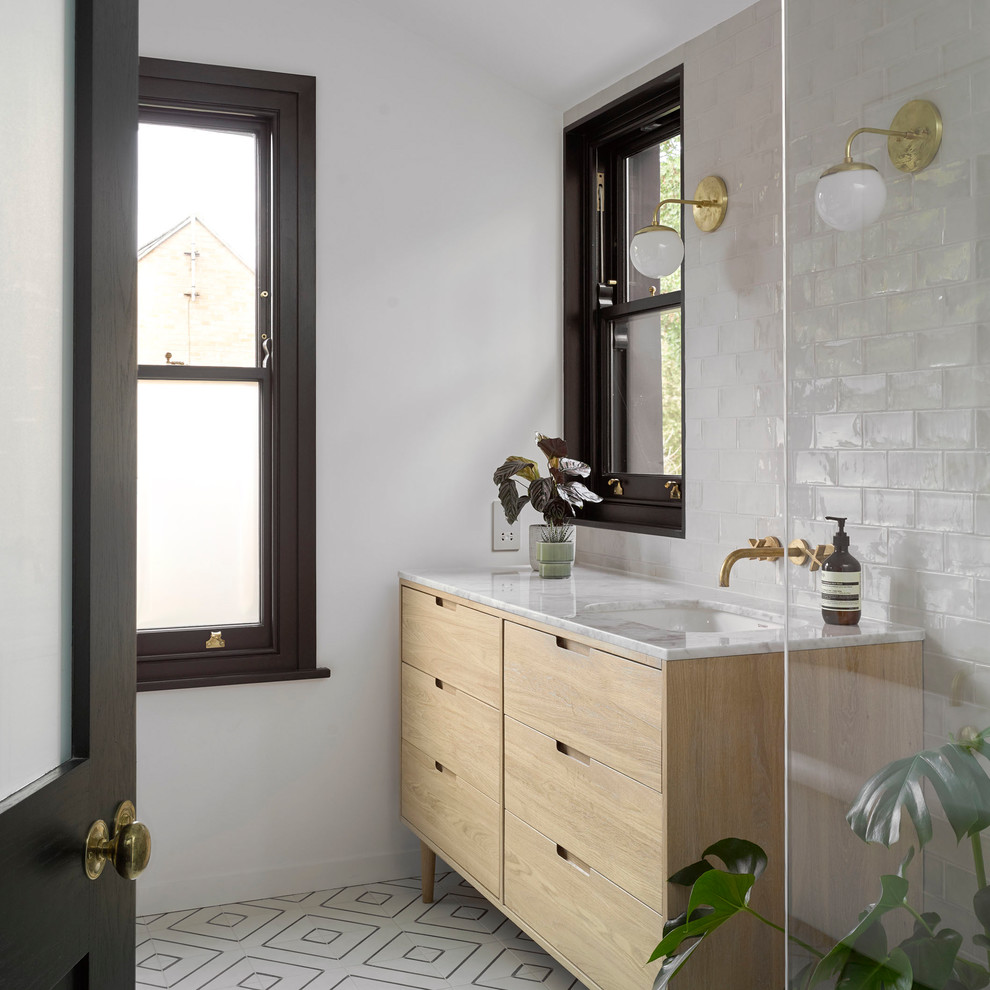 Modernes Badezimmer mit flächenbündigen Schrankfronten, hellen Holzschränken, weißen Fliesen, weißer Wandfarbe, Unterbauwaschbecken, buntem Boden und weißer Waschtischplatte in London