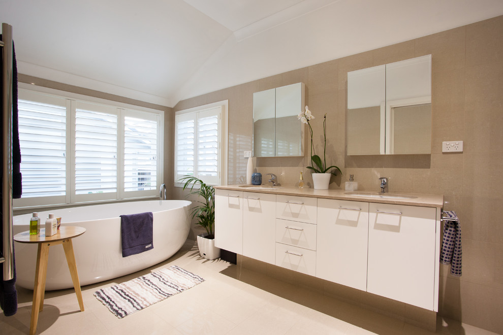 Идея дизайна: ванная комната в современном стиле с плоскими фасадами, белыми фасадами, отдельно стоящей ванной, бежевой плиткой, белыми стенами и врезной раковиной