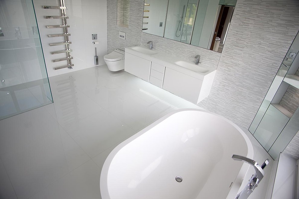 Exemple d'une grande salle de bain principale tendance avec un lavabo suspendu, des portes de placard blanches, une baignoire indépendante, une douche ouverte, WC suspendus, un carrelage blanc, des carreaux de porcelaine, un mur blanc et un sol en carrelage de porcelaine.