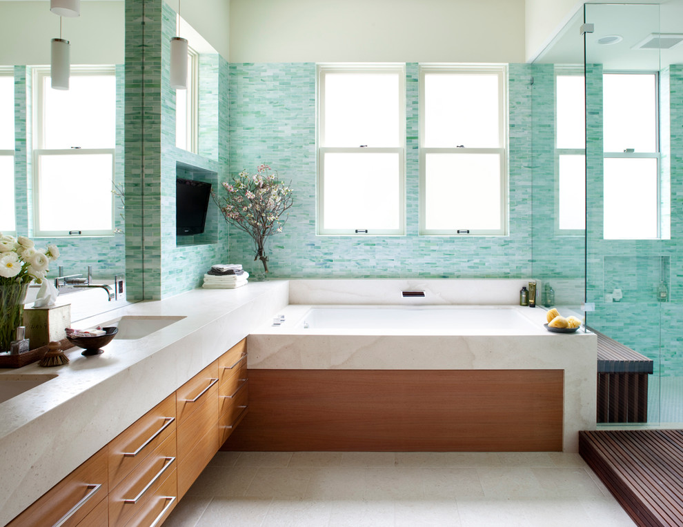 Cette image montre une salle de bain design en bois brun avec un lavabo encastré, un placard à porte plane, une baignoire encastrée et un carrelage bleu.