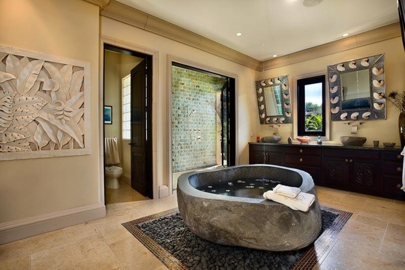 Photo of a large beach style ensuite bathroom in Hawaii with flat-panel cabinets, black cabinets, a freestanding bath, a two-piece toilet, beige tiles, ceramic tiles, beige walls, pebble tile flooring, a vessel sink, granite worktops and a walk-in shower.