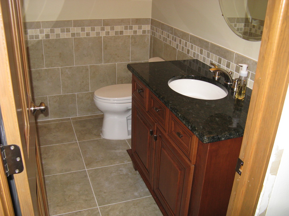 Example of a mid-sized classic 3/4 porcelain tile porcelain tile bathroom design in Detroit with raised-panel cabinets, medium tone wood cabinets, granite countertops, a one-piece toilet and an undermount sink