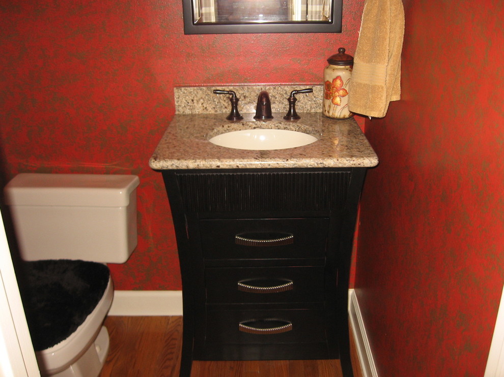 Ispirazione per una piccola stanza da bagno classica con lavabo sottopiano, consolle stile comò, ante in legno bruno, top in granito, WC a due pezzi, pareti rosse e parquet chiaro