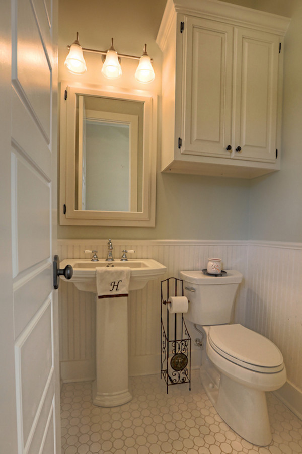 ニューオリンズにある高級なトラディショナルスタイルのおしゃれなバスルーム (浴槽なし) (ペデスタルシンク、レイズドパネル扉のキャビネット、白いキャビネット、分離型トイレ、白いタイル、磁器タイル、グレーの壁、磁器タイルの床) の写真
