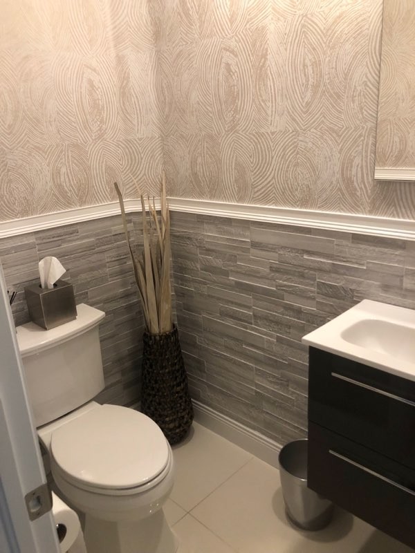 Small modern half tiled bathroom in Miami with flat-panel cabinets, grey cabinets, grey tiles, porcelain tiles, solid surface worktops, white floors and white worktops.