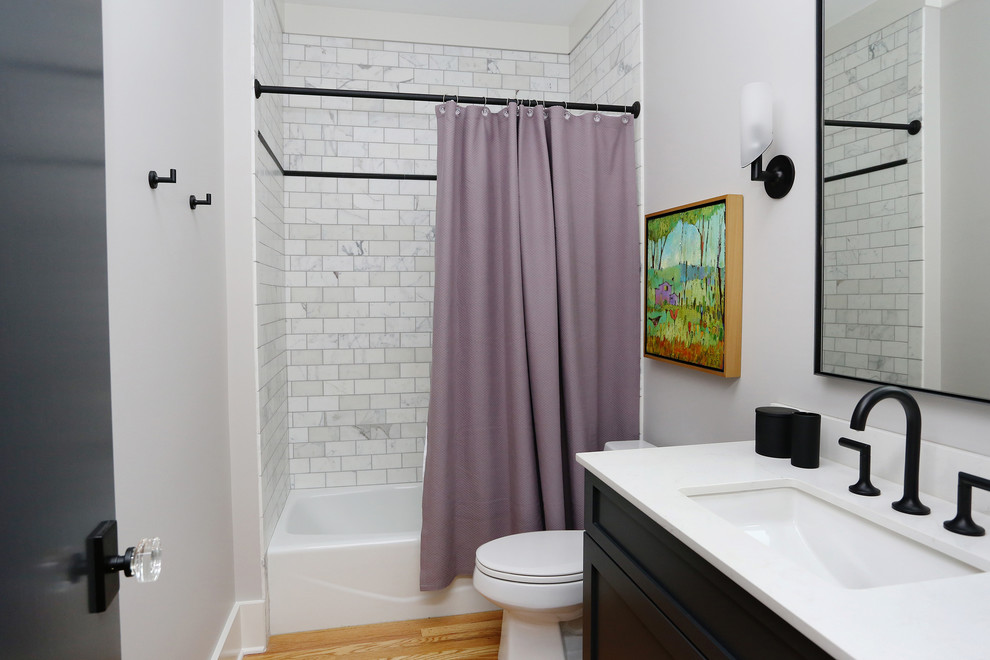 Bild på ett mellanstort funkis vit vitt badrum för barn, med skåp i shakerstil, svarta skåp, ett badkar i en alkov, en dusch/badkar-kombination, mellanmörkt trägolv, ett undermonterad handfat, bänkskiva i kvarts, en toalettstol med separat cisternkåpa, vit kakel, marmorkakel, grå väggar, orange golv och dusch med duschdraperi