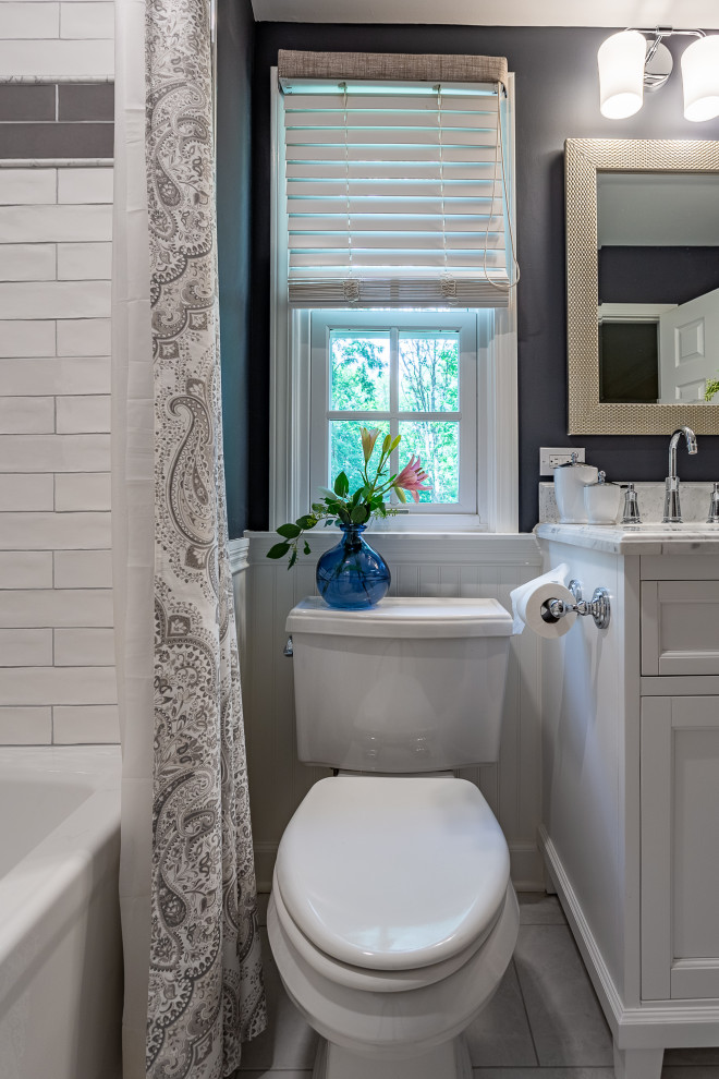 This is an example of a medium sized classic family bathroom in Chicago with shaker cabinets, white cabinets, an alcove bath, a shower/bath combination, a two-piece toilet, white tiles, ceramic tiles, grey walls, porcelain flooring, a submerged sink, marble worktops, grey floors, a shower curtain and white worktops.