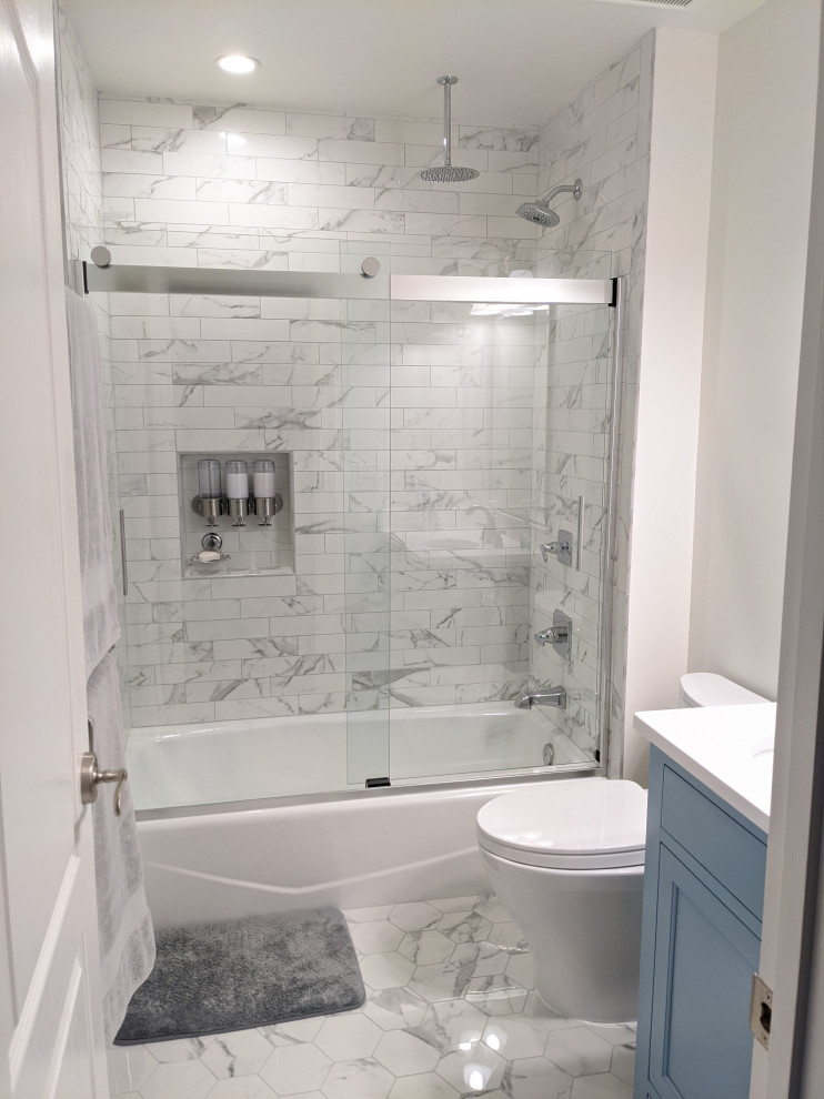 Design ideas for a medium sized classic family bathroom in DC Metro with flat-panel cabinets, blue cabinets, an alcove bath, a shower/bath combination, a two-piece toilet, white tiles, porcelain tiles, white walls, porcelain flooring, a submerged sink, quartz worktops, white floors, a sliding door and white worktops.