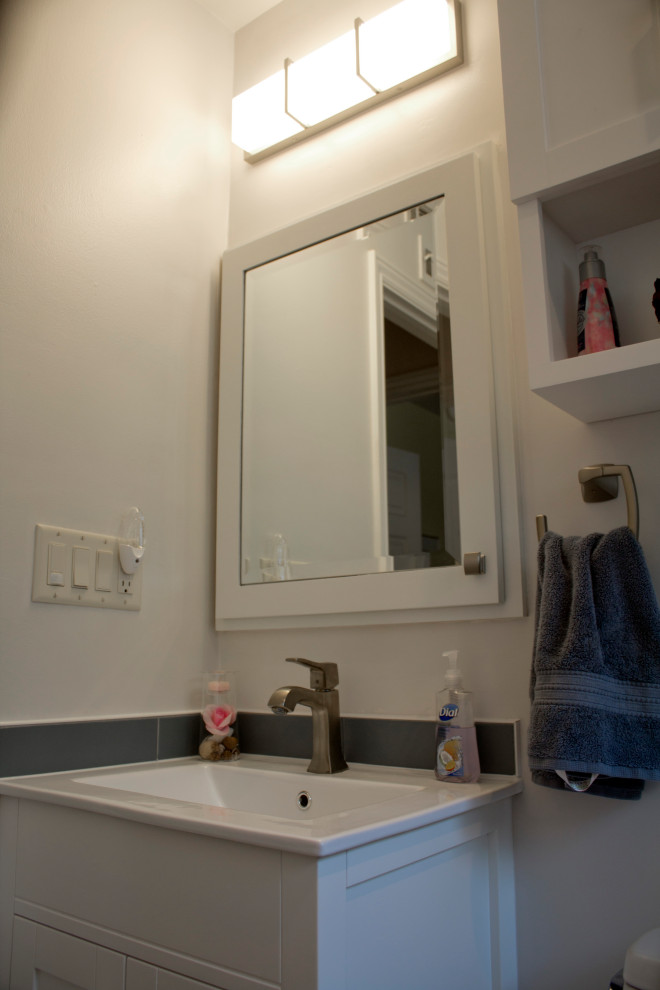 Idée de décoration pour une salle de bain minimaliste de taille moyenne avec un placard à porte shaker, des portes de placard blanches, une baignoire en alcôve, un combiné douche/baignoire, WC à poser, un carrelage bleu, des carreaux de céramique, un mur blanc, un sol en carrelage de céramique, un lavabo intégré, un plan de toilette en surface solide, un sol multicolore, une cabine de douche à porte coulissante et un plan de toilette blanc.