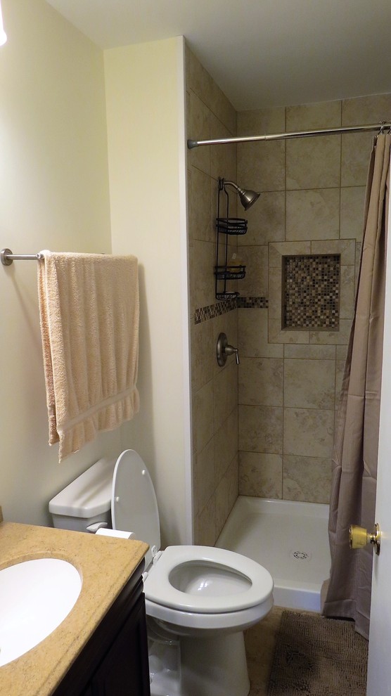 Inredning av ett klassiskt litet en-suite badrum, med luckor med upphöjd panel, skåp i mörkt trä, en dusch i en alkov, en toalettstol med hel cisternkåpa, beige kakel, porslinskakel, gula väggar, klinkergolv i keramik och granitbänkskiva