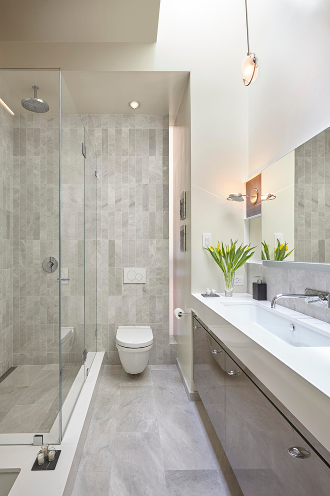 Design ideas for a contemporary bathroom in San Francisco with a submerged sink, flat-panel cabinets, grey cabinets, a corner shower, a wall mounted toilet, grey tiles and white walls.