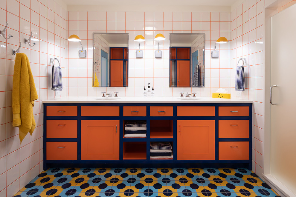 Idée de décoration pour une douche en alcôve bohème avec un placard à porte shaker, des portes de placard oranges, un carrelage blanc, un mur blanc, un lavabo encastré, un sol multicolore, une cabine de douche à porte battante et un plan de toilette blanc.