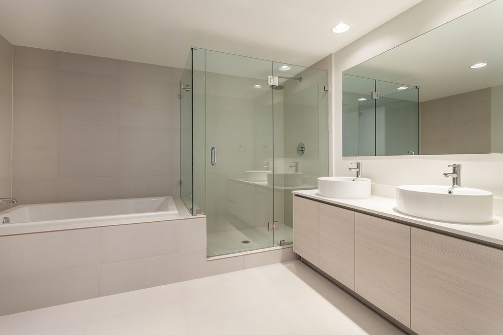 Medium sized contemporary ensuite bathroom in Miami with flat-panel cabinets, light wood cabinets, a one-piece toilet, beige tiles, white walls, a built-in bath, a corner shower, cement tiles, porcelain flooring, a vessel sink, engineered stone worktops, beige floors and a hinged door.