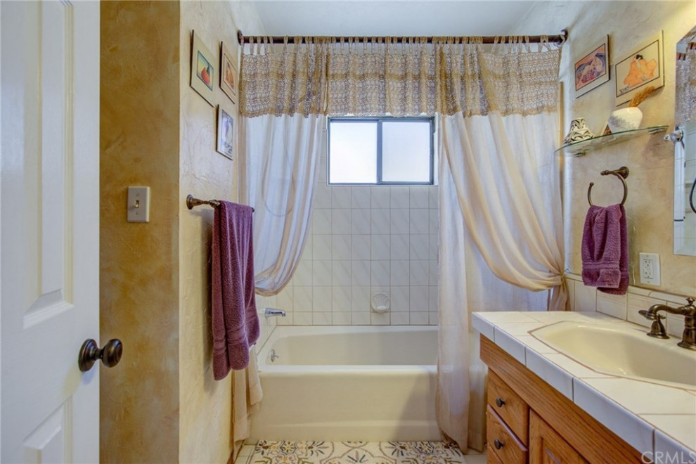 Photo of a medium sized traditional shower room bathroom in Los Angeles with raised-panel cabinets, light wood cabinets, an alcove bath, a shower/bath combination, white tiles, porcelain tiles, brown walls, an integrated sink, tiled worktops, a shower curtain and white worktops.