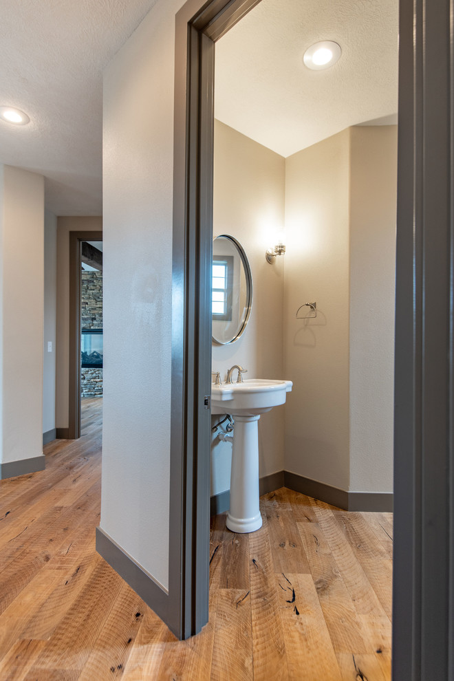 Foto di una stanza da bagno rustica con WC monopezzo, pareti beige, parquet chiaro, lavabo a colonna e pavimento marrone