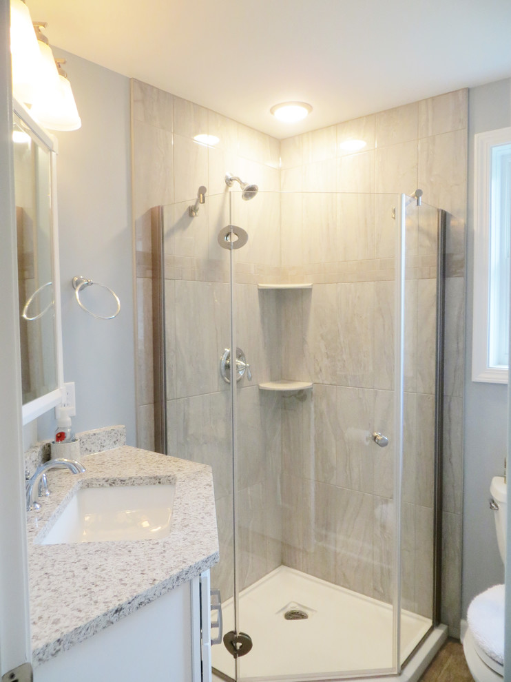 Small transitional 3/4 gray tile and porcelain tile ceramic tile and beige floor corner shower photo in New York with flat-panel cabinets, white cabinets, a one-piece toilet, gray walls, a wall-mount sink, quartz countertops, a hinged shower door and gray countertops