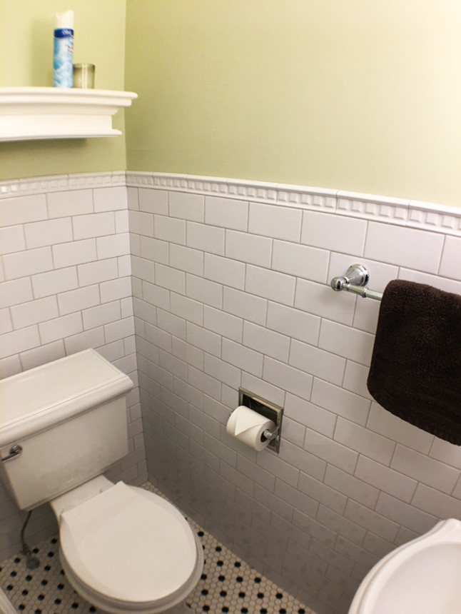 Inredning av ett klassiskt litet badrum med dusch, med en toalettstol med separat cisternkåpa, vit kakel, tunnelbanekakel, gula väggar, mosaikgolv och ett väggmonterat handfat