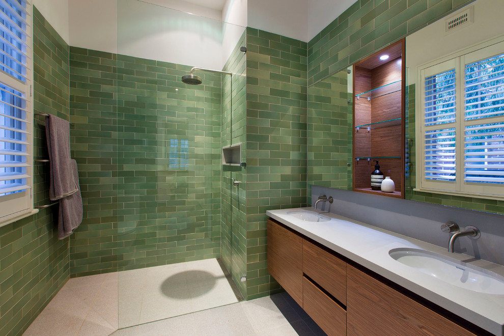 Diseño de cuarto de baño actual con lavabo bajoencimera, armarios con paneles lisos, puertas de armario de madera oscura, ducha a ras de suelo, baldosas y/o azulejos verdes y baldosas y/o azulejos de cemento