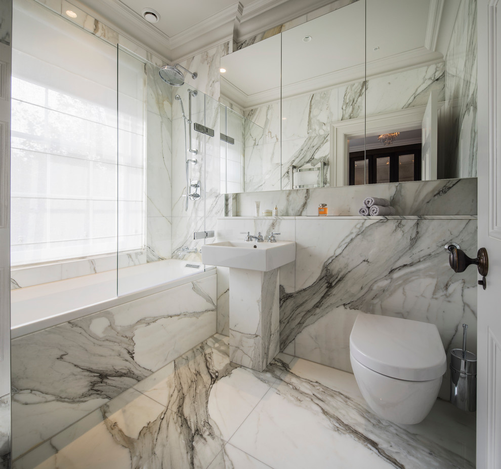 Inredning av ett modernt litet en-suite badrum, med ett platsbyggt badkar, en dusch/badkar-kombination, en vägghängd toalettstol, ett piedestal handfat, släta luckor, vit kakel, stenkakel och med dusch som är öppen