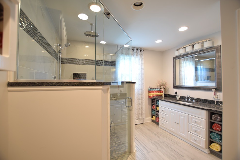 Inredning av ett modernt stort badrum med dusch, med luckor med upphöjd panel, vita skåp, en kantlös dusch, en toalettstol med separat cisternkåpa, svart och vit kakel, keramikplattor, grå väggar, klinkergolv i porslin, ett undermonterad handfat, granitbänkskiva, grått golv och dusch med gångjärnsdörr