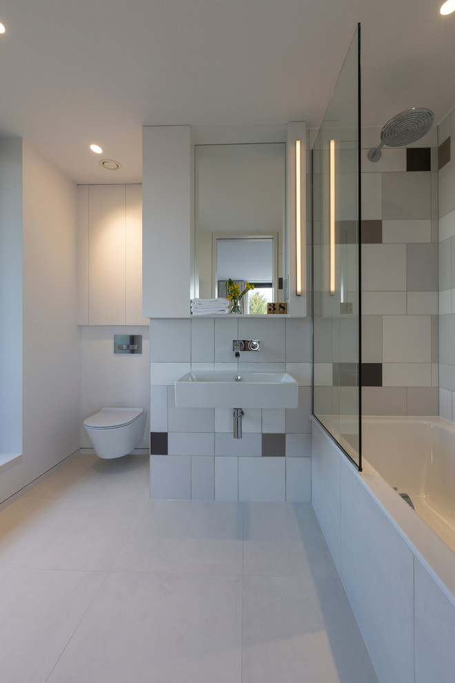 Cette photo montre une salle de bain tendance de taille moyenne avec un combiné douche/baignoire, WC suspendus, un lavabo suspendu, un sol gris, aucune cabine, une baignoire en alcôve et un mur blanc.