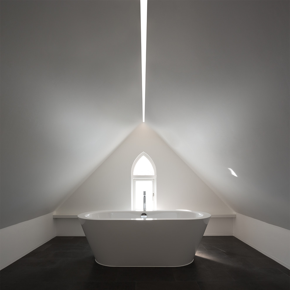 Example of a minimalist master stone tile freestanding bathtub design in London with white cabinets and white walls