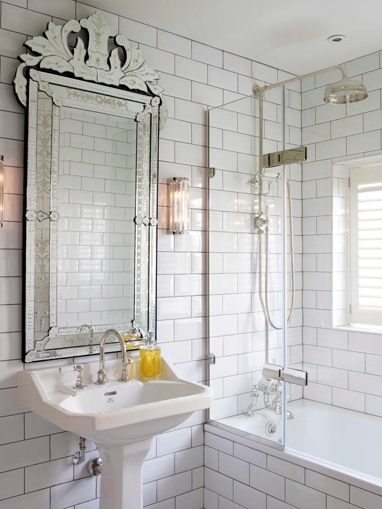 Bild på ett mellanstort vintage badrum, med ett platsbyggt badkar, en dusch/badkar-kombination, en toalettstol med hel cisternkåpa, vit kakel, vita väggar, mosaikgolv, ett piedestal handfat, vitt golv, dusch med gångjärnsdörr och tunnelbanekakel