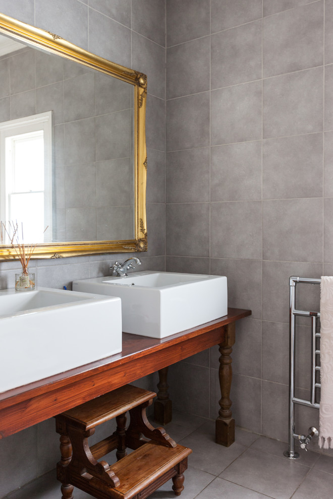 На фото: ванная комната в стиле неоклассика (современная классика) с настольной раковиной, столешницей из дерева и серой плиткой