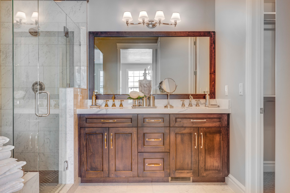 Idée de décoration pour une salle de bain tradition en bois brun avec un placard à porte shaker, un carrelage gris, un carrelage blanc, un lavabo encastré, un sol blanc, une cabine de douche à porte battante et un plan de toilette blanc.