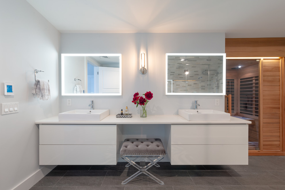 Contemporary bathroom in New York with flat-panel cabinets, white cabinets, grey walls, a vessel sink, grey floors and white worktops.