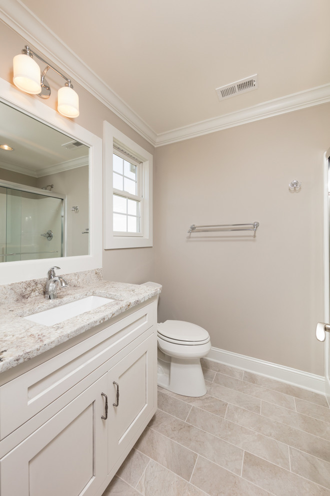 Foto på ett mellanstort vintage badrum med dusch, med luckor med infälld panel, vita skåp, beige väggar, klinkergolv i porslin, ett undermonterad handfat och granitbänkskiva
