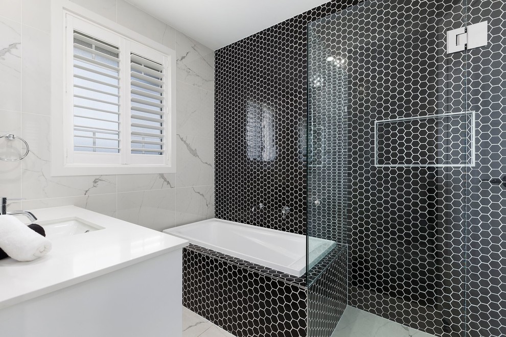 Modern inredning av ett badrum med dusch, med ett hörnbadkar, en hörndusch, svart kakel, ett undermonterad handfat och dusch med gångjärnsdörr