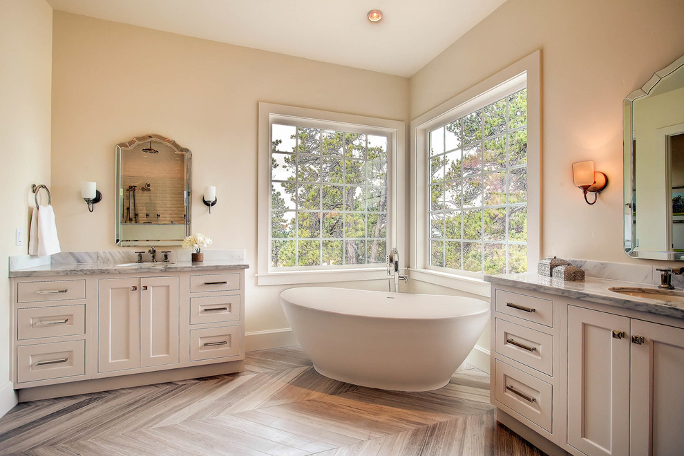 Klassisches Badezimmer mit Unterbauwaschbecken, Schrankfronten im Shaker-Stil, weißen Schränken, freistehender Badewanne, beiger Wandfarbe und braunem Holzboden in Denver