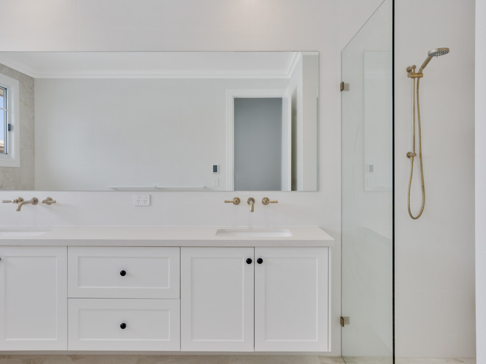 This is an example of a large coastal ensuite bathroom in Brisbane with shaker cabinets, white cabinets, a freestanding bath, a double shower, a wall mounted toilet, beige tiles, marble tiles, beige walls, marble flooring, a submerged sink, marble worktops, beige floors, an open shower, yellow worktops, double sinks and a floating vanity unit.
