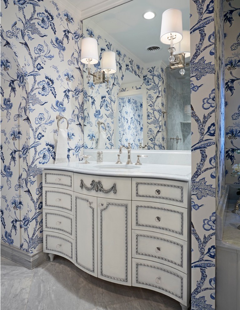 Klassisk inredning av ett badrum, med ett undermonterad handfat, vita skåp, flerfärgade väggar och luckor med infälld panel