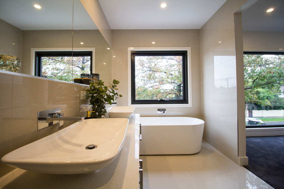 Modern inredning av ett litet en-suite badrum, med ett fristående badkar, en öppen dusch, en vägghängd toalettstol, beige kakel, porslinskakel, beige väggar, cementgolv, bänkskiva i betong och beiget golv