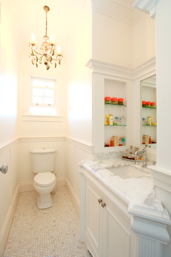 Modelo de cuarto de baño clásico de tamaño medio con armarios con paneles empotrados, encimera de mármol, sanitario de una pieza, baldosas y/o azulejos blancos y paredes blancas