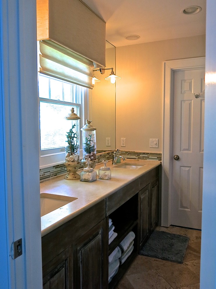 Klassisk inredning av ett mellanstort badrum, med ett undermonterad handfat, luckor med upphöjd panel, skåp i slitet trä, bänkskiva i kalksten, en toalettstol med separat cisternkåpa, flerfärgad kakel, glaskakel, gröna väggar och marmorgolv