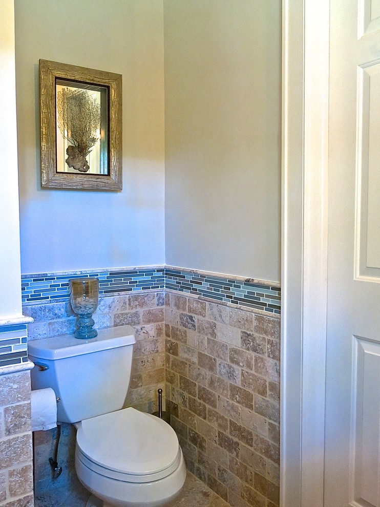 Bild på ett mellanstort vintage toalett, med ett undermonterad handfat, luckor med upphöjd panel, skåp i slitet trä, bänkskiva i kalksten, en toalettstol med separat cisternkåpa, flerfärgad kakel, glaskakel, gröna väggar och marmorgolv