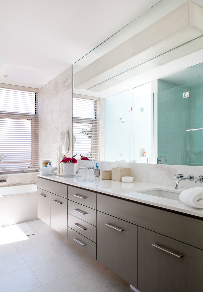 Example of a mid-sized trendy master white tile marble floor corner bathtub design in New York with flat-panel cabinets, medium tone wood cabinets, white walls, an undermount sink and limestone countertops