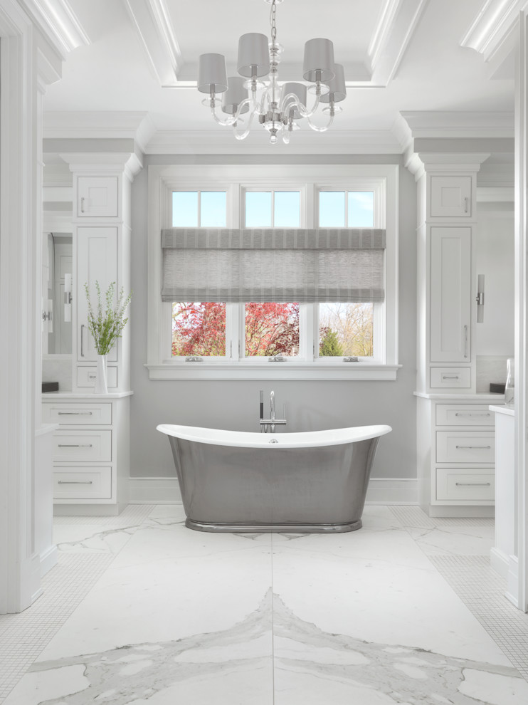 Modelo de cuarto de baño principal tradicional extra grande con armarios estilo shaker, puertas de armario blancas, bañera exenta, suelo blanco, paredes grises y suelo de mármol
