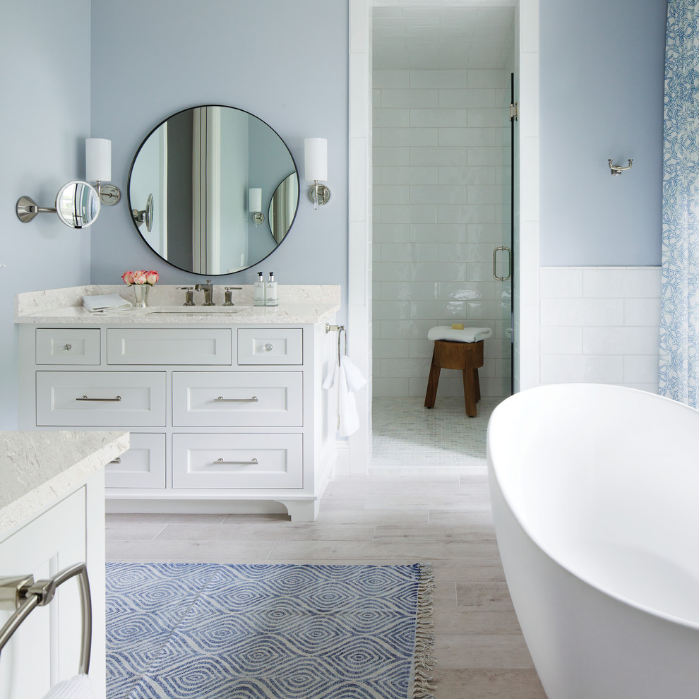 Nautical ensuite wet room bathroom in Minneapolis with recessed-panel cabinets, white cabinets, a freestanding bath, white tiles, blue walls, a submerged sink, beige floors and a hinged door.