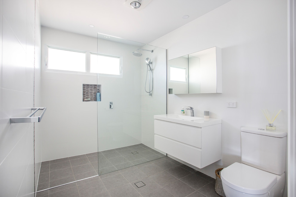 This is an example of a small contemporary bathroom in Wollongong with flat-panel cabinets, white cabinets, an alcove shower, a two-piece toilet, white tiles, porcelain tiles, ceramic flooring, an integrated sink, granite worktops, grey floors and an open shower.