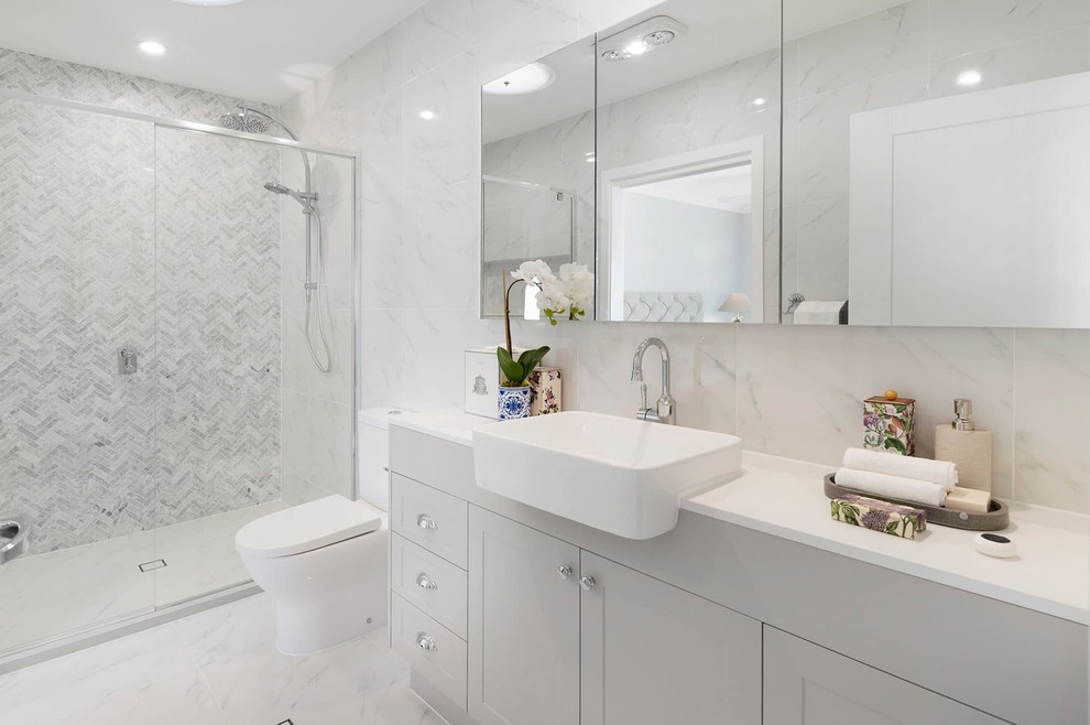 Пример оригинального дизайна: главная ванная комната в морском стиле с фасадами в стиле шейкер, серыми фасадами, душем в нише, унитазом-моноблоком, серой плиткой, белой плиткой, мраморной плиткой, серыми стенами, накладной раковиной, серым полом, душем с раздвижными дверями и белой столешницей
