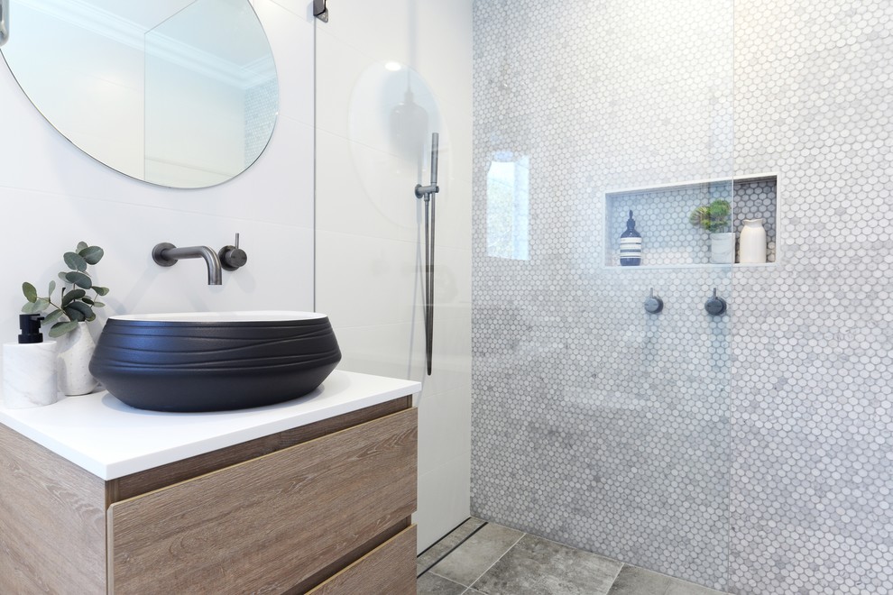Mid-sized eclectic master white tile and ceramic tile ceramic tile and beige floor double shower photo with flat-panel cabinets, light wood cabinets, a one-piece toilet, white walls, a vessel sink, solid surface countertops and a hinged shower door