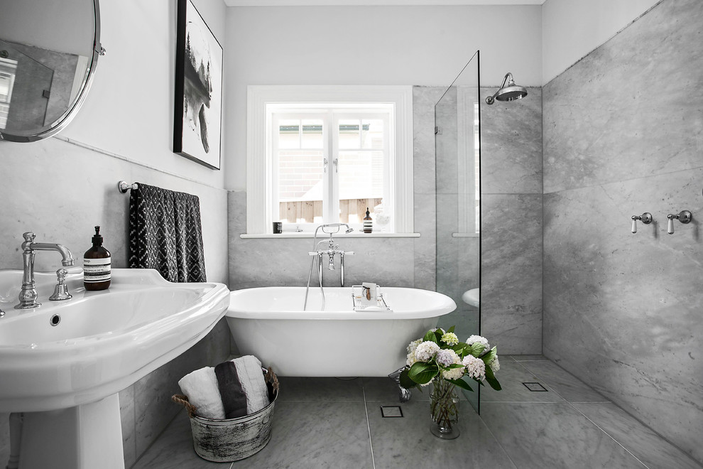 На фото: ванная комната среднего размера в стиле неоклассика (современная классика) с ванной на ножках, душем в нише, унитазом-моноблоком, серой плиткой, мраморной плиткой, серыми стенами, мраморным полом, раковиной с пьедесталом, серым полом и открытым душем с