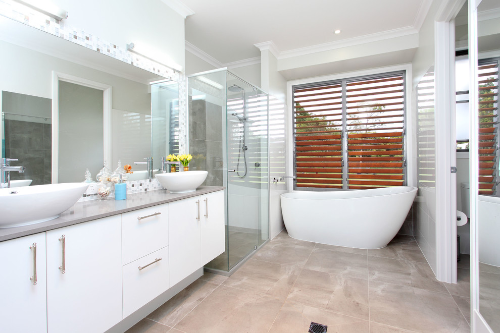 Пример оригинального дизайна: ванная комната в современном стиле с настольной раковиной, плоскими фасадами, белыми фасадами, отдельно стоящей ванной, душем в нише, плиткой мозаикой, серой столешницей и окном